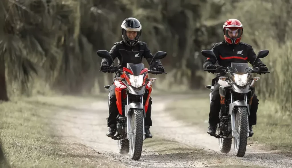 dois pilotos em suas motocicletas honda xre 190 2024 uma vermelha e outra preta em uma estrada de terra - Moto Honda Motopel