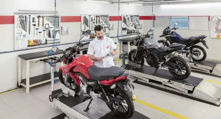 concessionaria honda colaborador fazendo cheklist de uma moto honda vermelha com outras duas motocicletas aguardando vistoria - Moto Honda Motopel