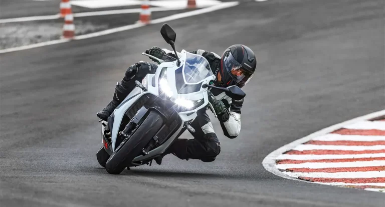 piloto fazendo curva em sua motocicleta com farois ligados - Moto Honda Motopel